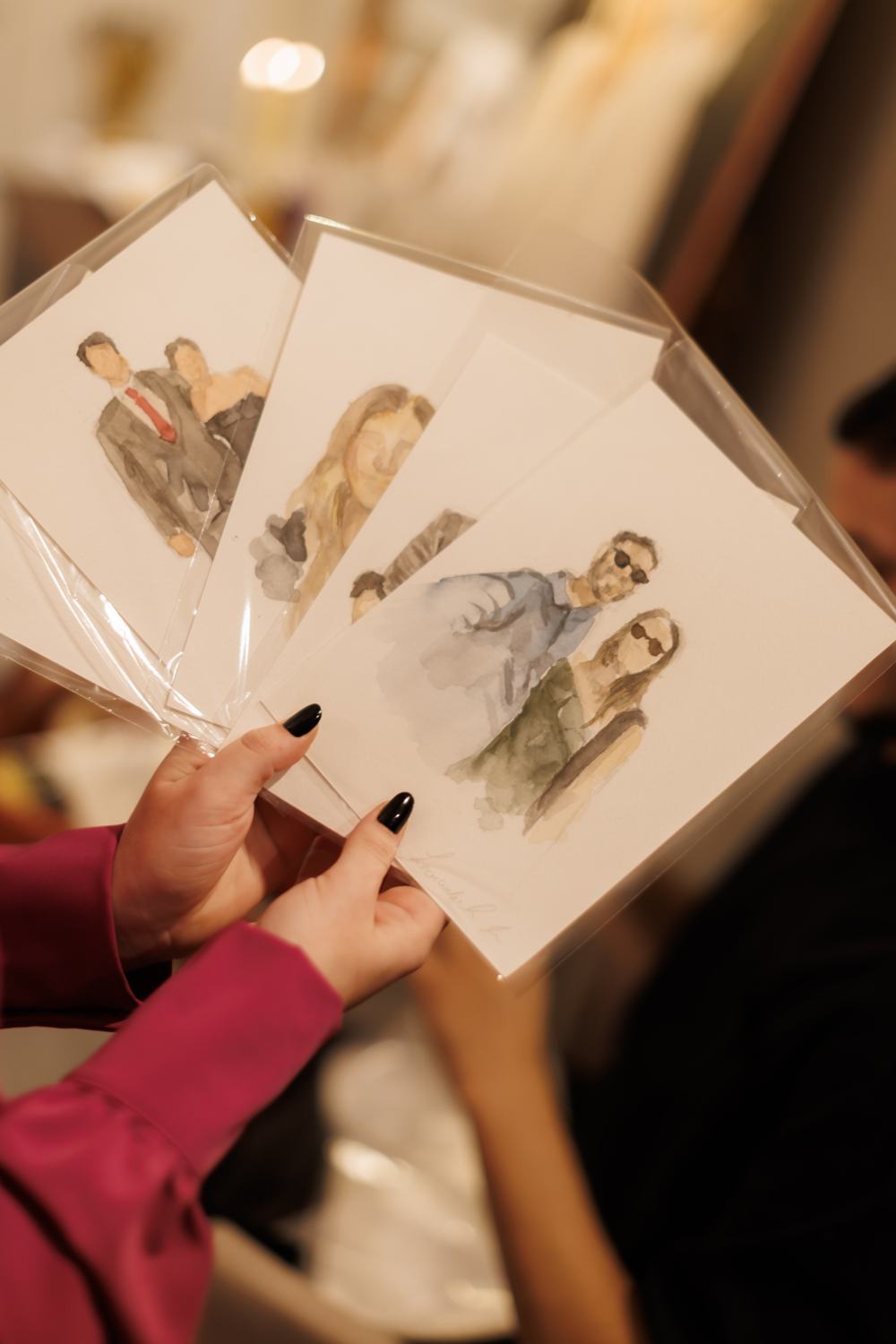 Convidada segurando retratos em aquarela recém-pintados